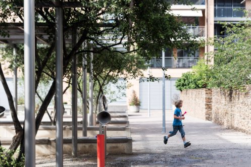 Kind springt von rechts nach links über den Weg zum Spielplatz, Foto: Robert Adam